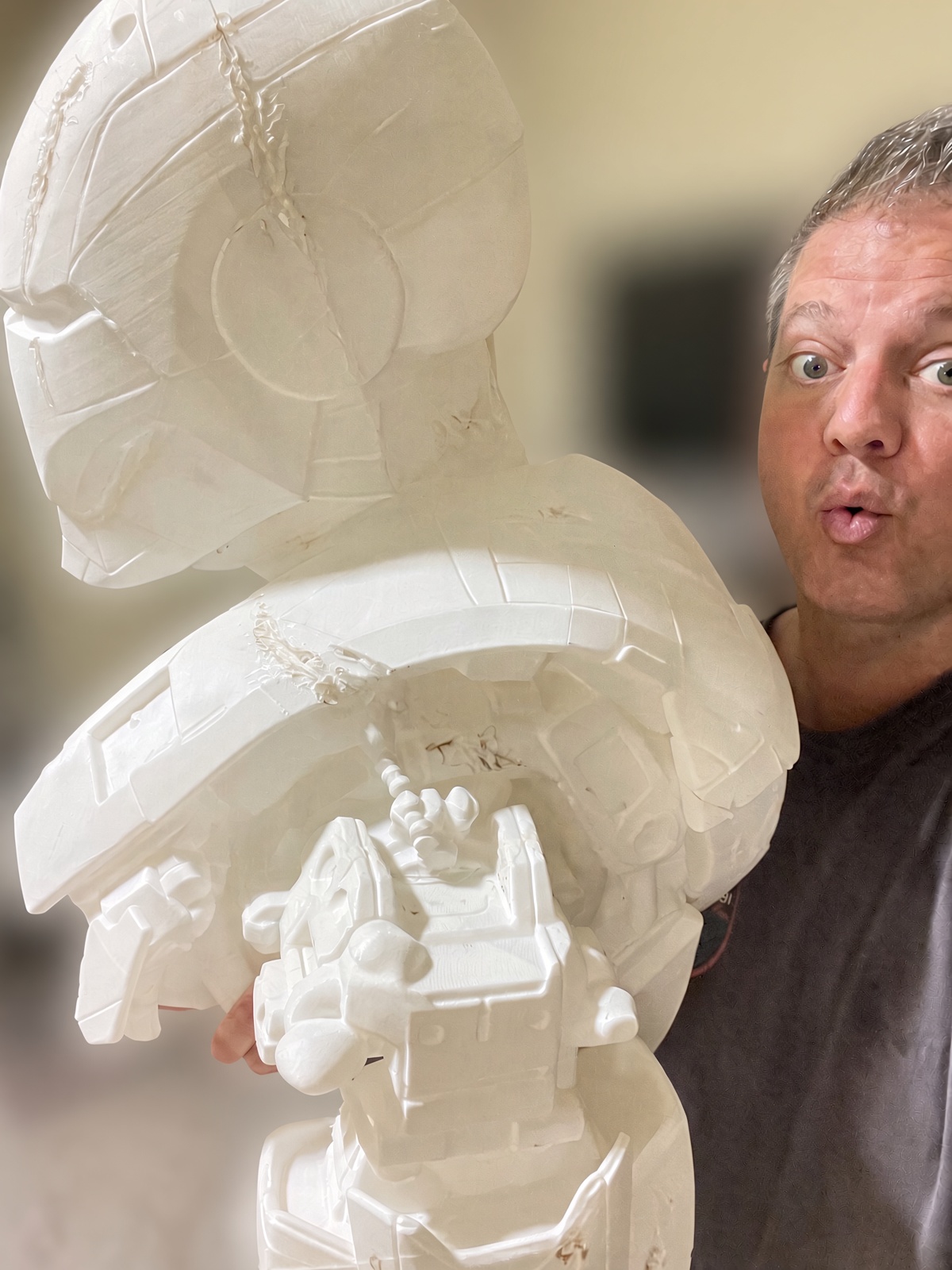 Matt Baribeau holding a large assembled armored bust straight off the printer