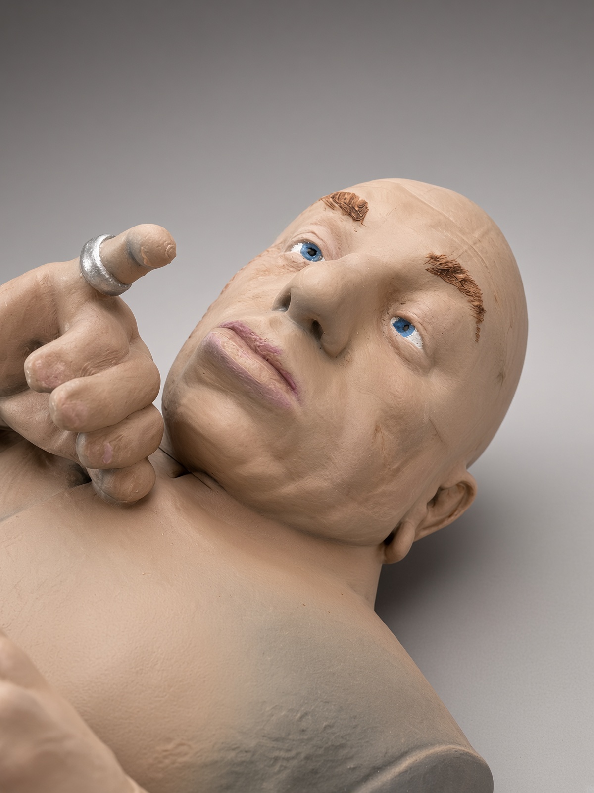 Close up of a hand-painted figurine face and pinky ring
