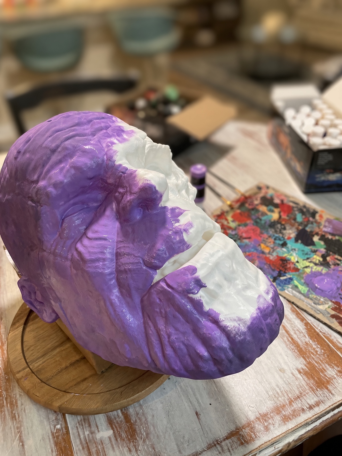A sculpted head being base coated in purple